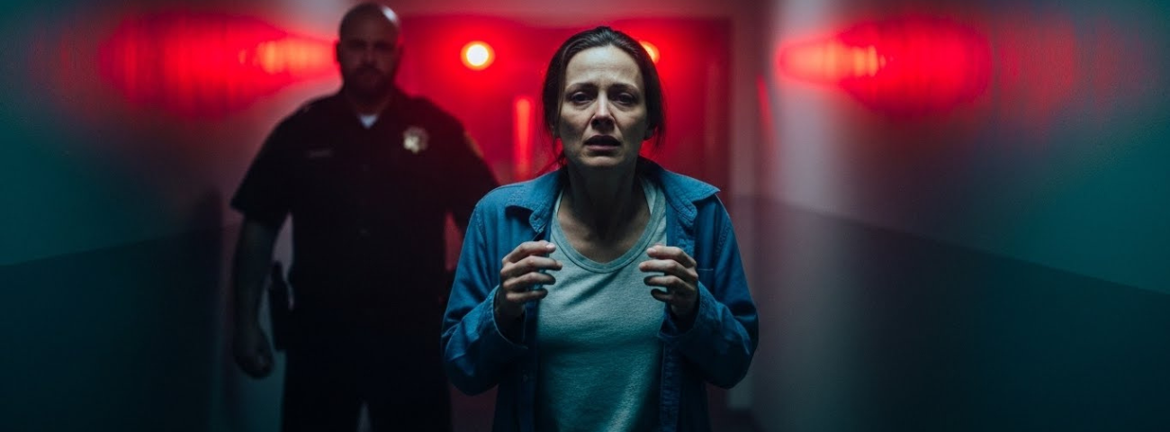 A distressed woman walks down a dim institutional hallway as an authority figure follows, symbolizing fear, trauma, and the failure of institutions to protect survivors in Illinois.