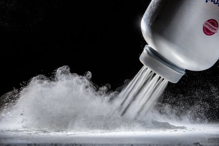 Talcum powder being poured from a bottle, illustrating long-term consumer exposure linked to ovarian cancer and asbestos-related lawsuits.