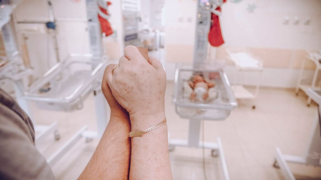 NEC baby formula lawsuit: parent’s hands clasped together in a hospital nursery
