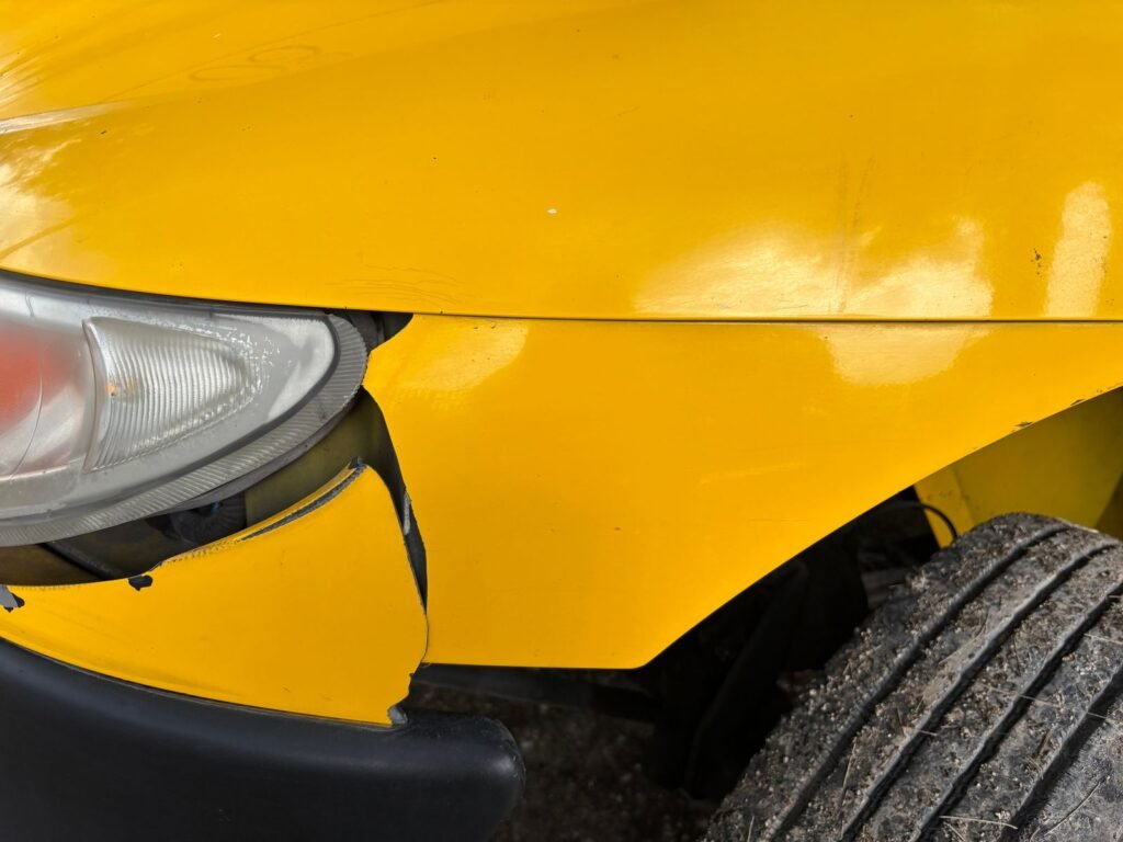 Car accident claim: close-up of a car's dented front bumper and cracked headlight after a collision