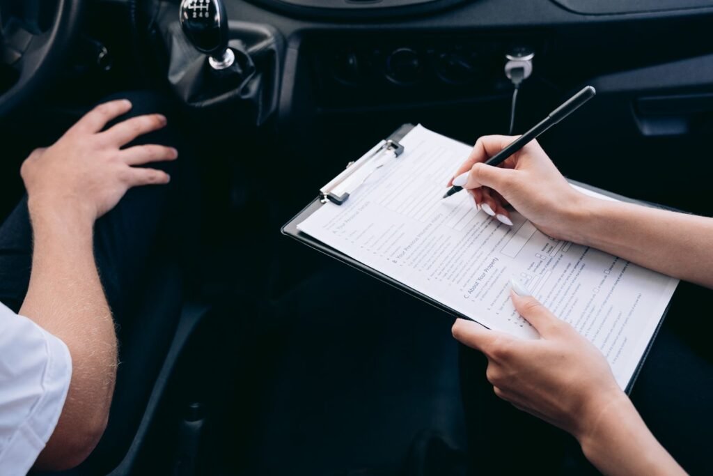 Car accident claim: hands writing notes on a clipboard inside a car next to the gear shift