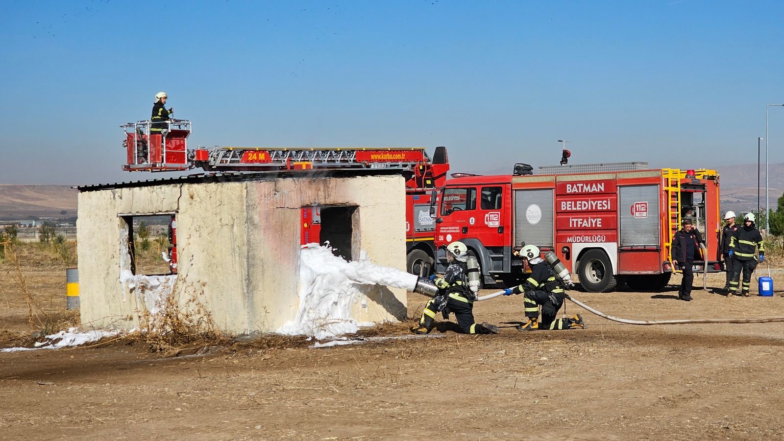 AFFF lawsuit update: firefighters using foam during an outdoor training drill beside a ladder truck