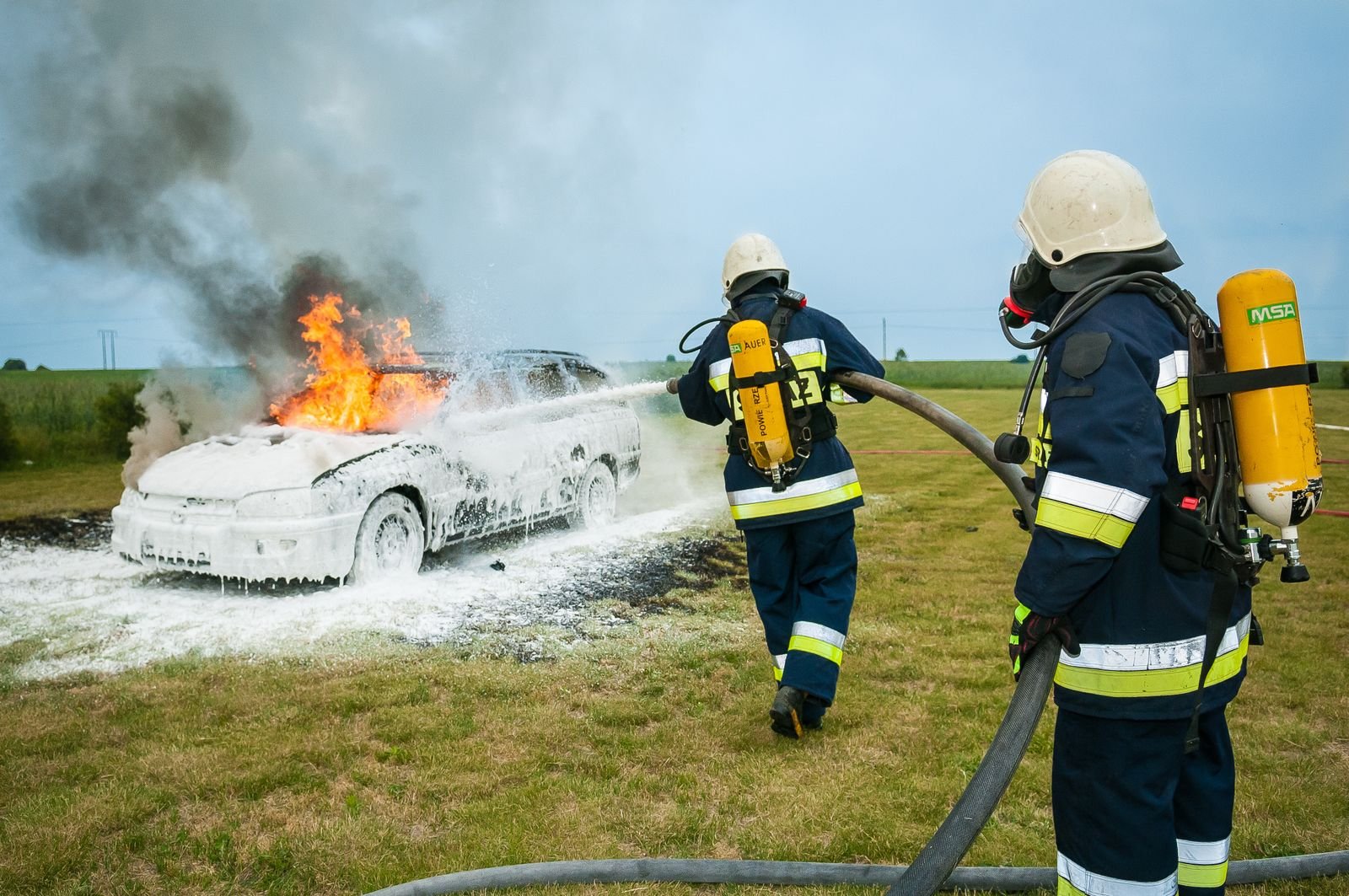 AFFF MDL: firefighters spraying foam on a burning vehicle, faces not visible