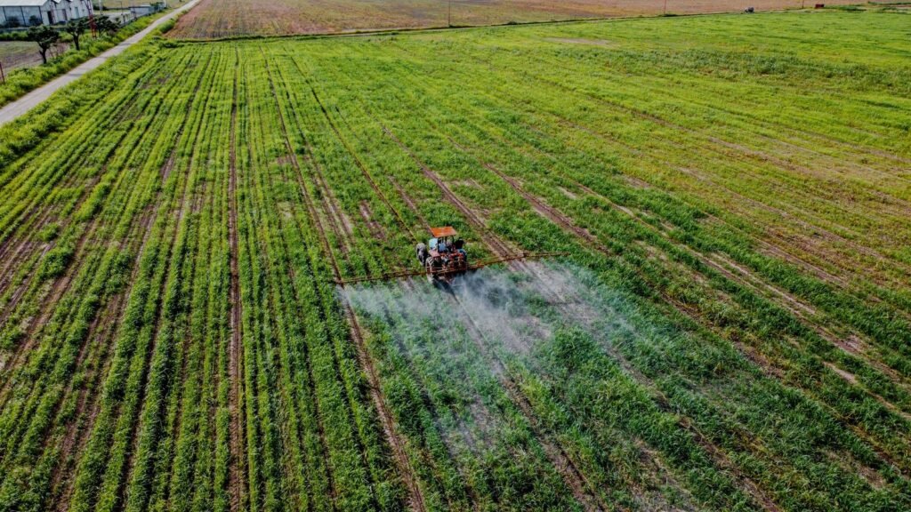 Chlorpyrifos lawsuit: aerial view of a tractor spraying crops across a large green field