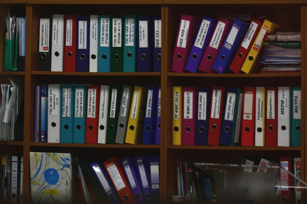 CIW sexual abuse claim: rows of colorful ring binders on wooden office shelves