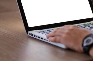 Dupixent lymphoma: hand resting on a laptop keyboard with a blank screen, ready to fill out an online form