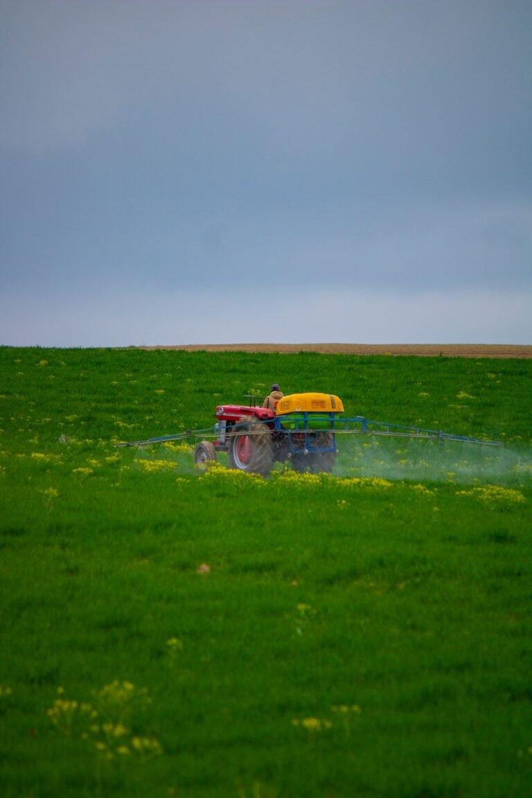 Chlorpyrifos Parkinson's lawsuit: tractor spraying pesticide across a green farm field under a cloudy sky