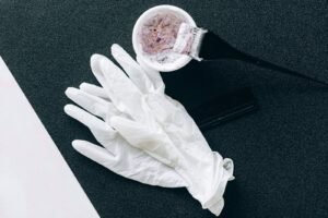 Hair relaxer lawsuit for salon workers: salon supplies on a table: white gloves, a dye brush, a mixing bowl and a comb