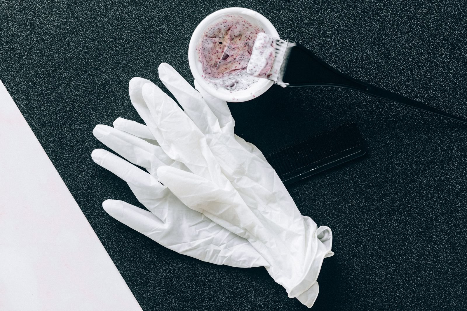 Hair relaxer lawsuit for salon workers: salon supplies on a table: white gloves, a dye brush, a mixing bowl and a comb