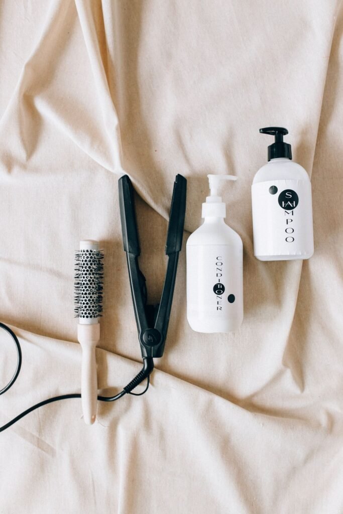 FDA formaldehyde ban: flat lay of a hairbrush, flat iron and shampoo bottles on white fabric