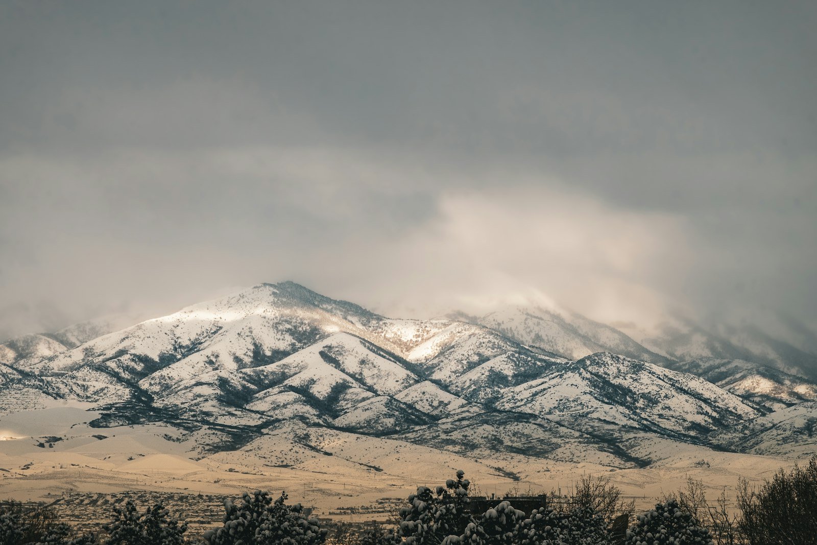 Snow-covered Utah mountain range under a cloudy sky