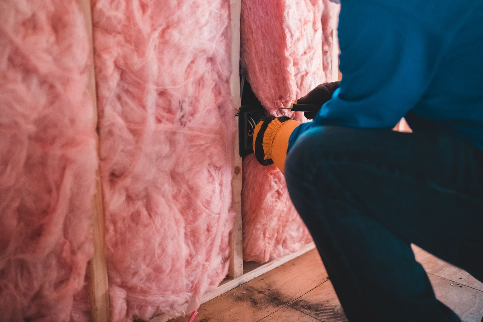 Mesothelioma compensation: gloved worker installing insulation inside a building, face not shown