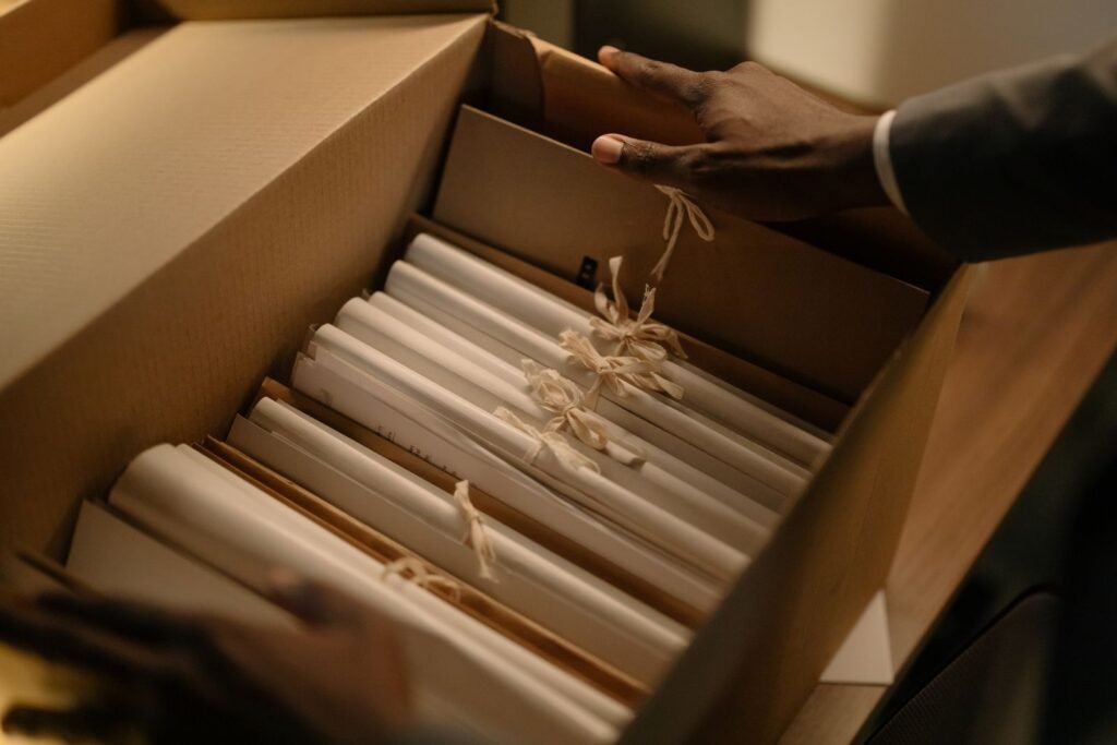 Mesothelioma evidence standards: hands sorting file folders inside a cardboard archive box