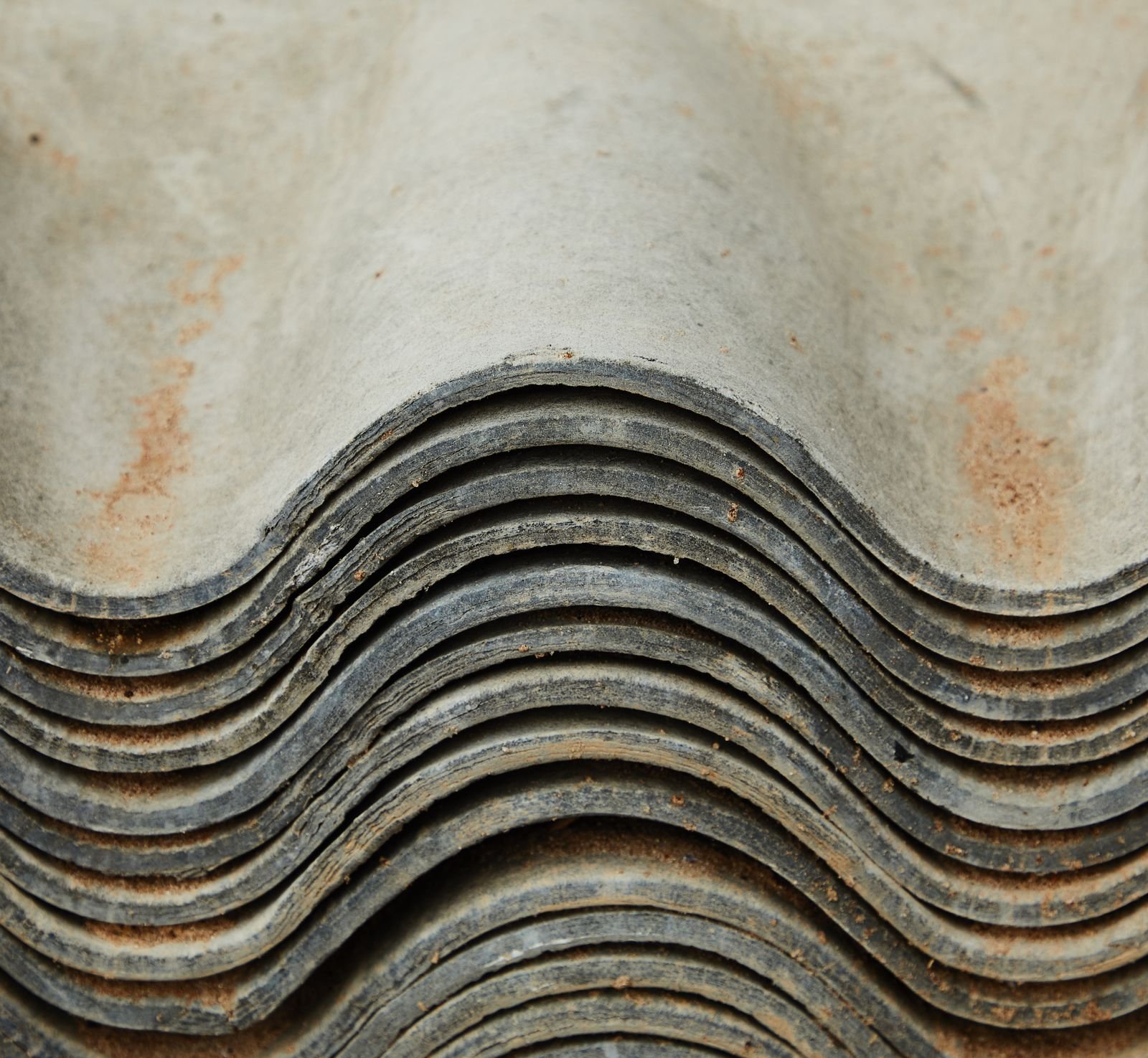 Mesothelioma lawsuits: stack of weathered corrugated roofing sheets showing age and wear