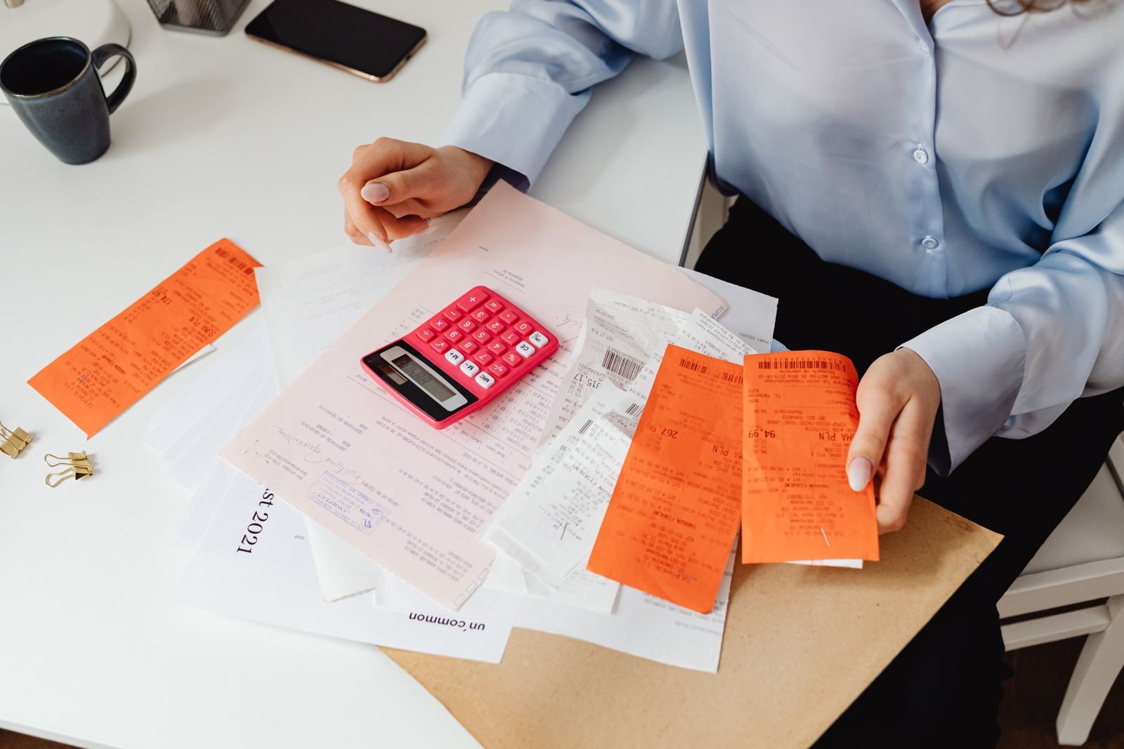 Motor vehicle accident compensation: hands holding receipts while using a calculator on a desk