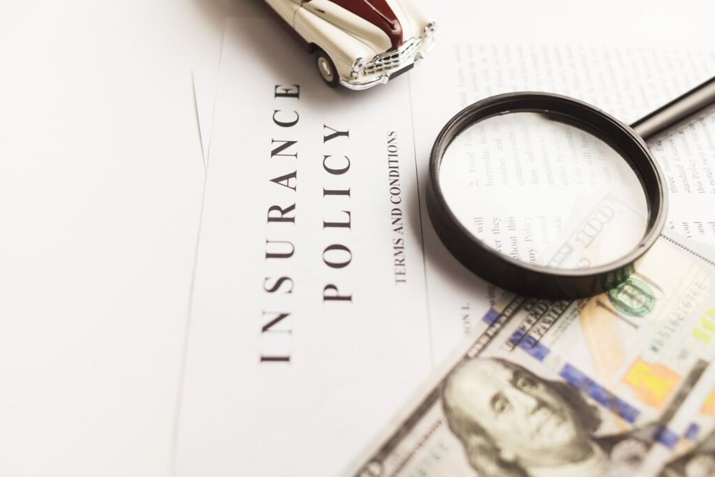 Motor vehicle accident compensation: magnifying glass over an insurance policy with money and a toy car