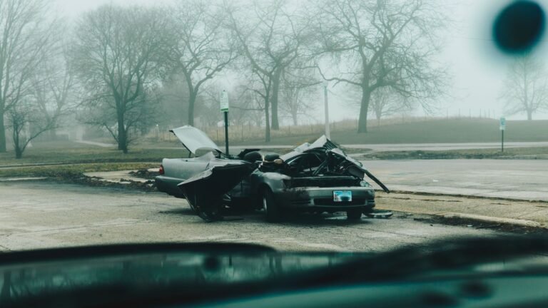 Motor vehicle accident lawsuit steps: badly damaged car on a quiet, foggy city street after a crash