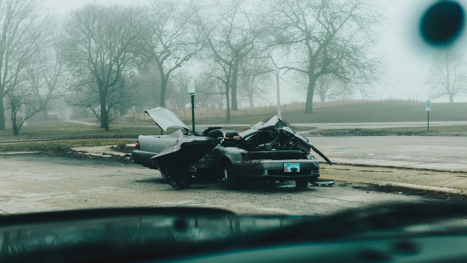 Motor vehicle accident lawsuit steps: badly damaged car on a quiet, foggy city street after a crash