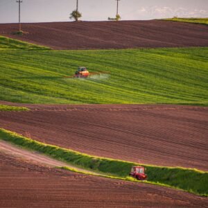 Paraquat lawsuits: tractors spraying crop fields at sunset across green and plowed farmland