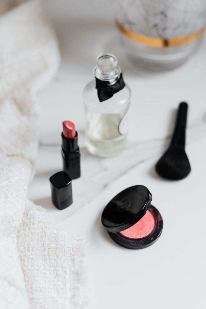 PFAS lawsuit: flat lay of lipstick, blush and a perfume bottle on marble
