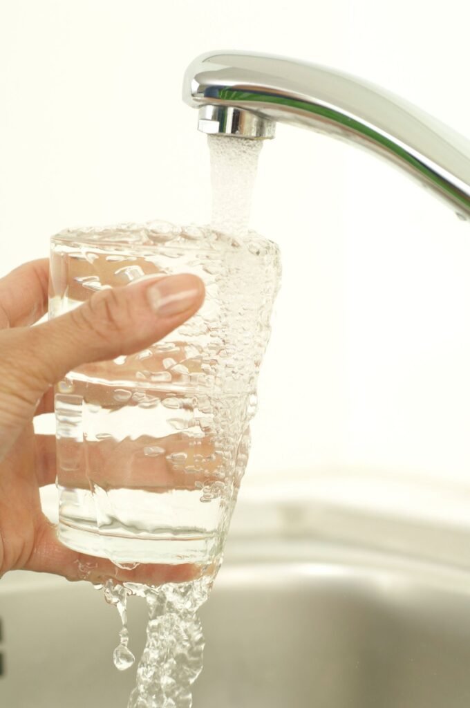 PFAS lawsuits: hand holding a glass being filled with tap water