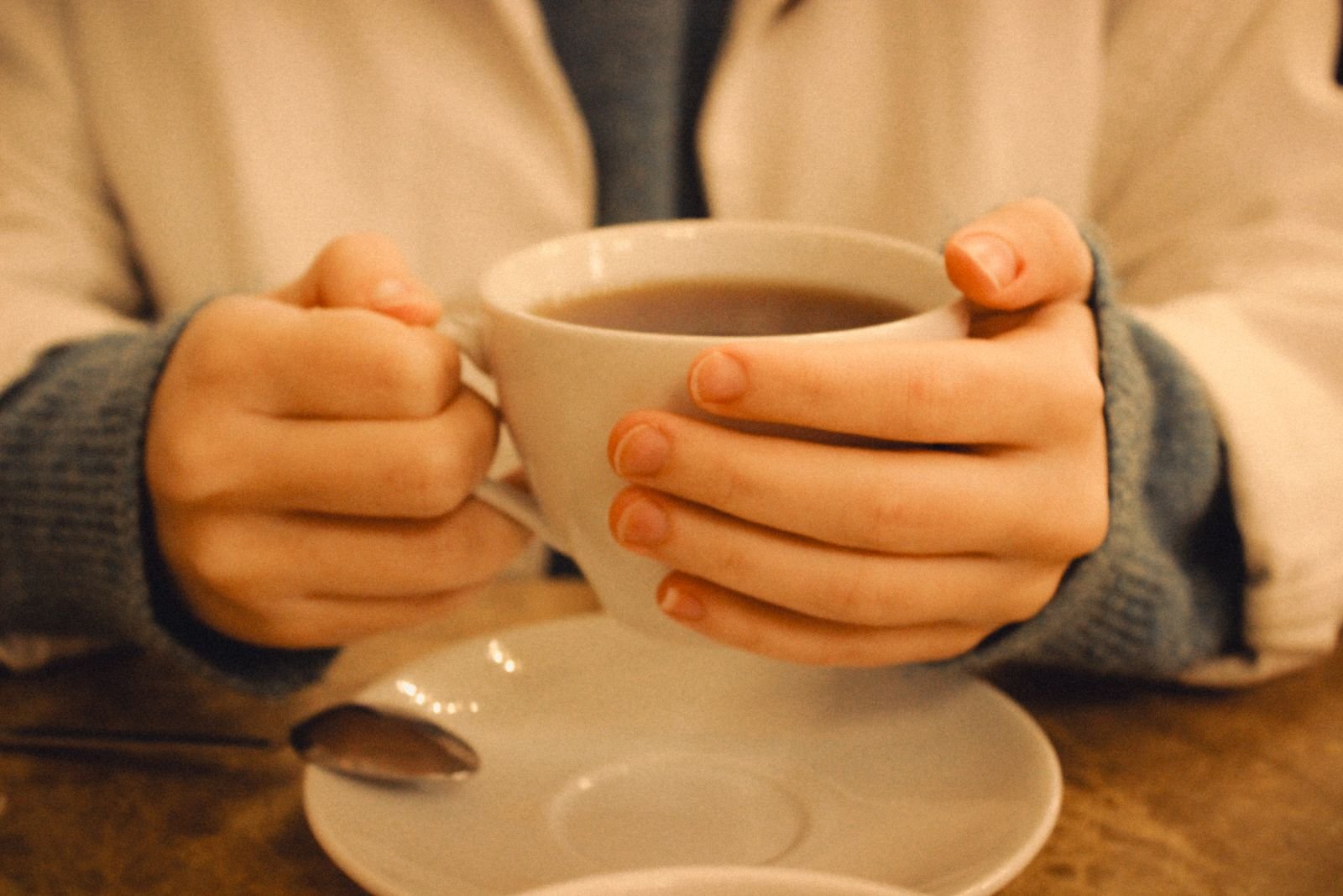 Roblox claims: hands holding a warm cup of coffee indoors in soft light