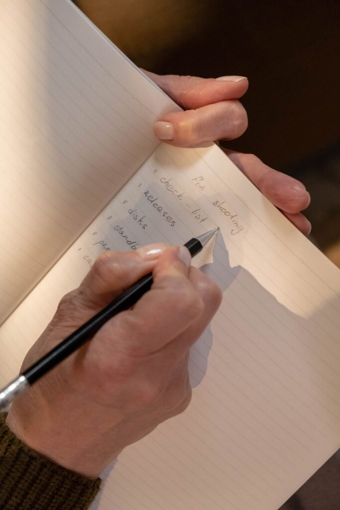Roblox claims: hands writing a list in a notebook with a pencil