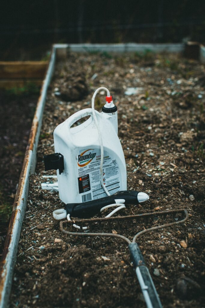 Roundup lawsuit for homeowners: garden spray container sitting on soil in a raised bed