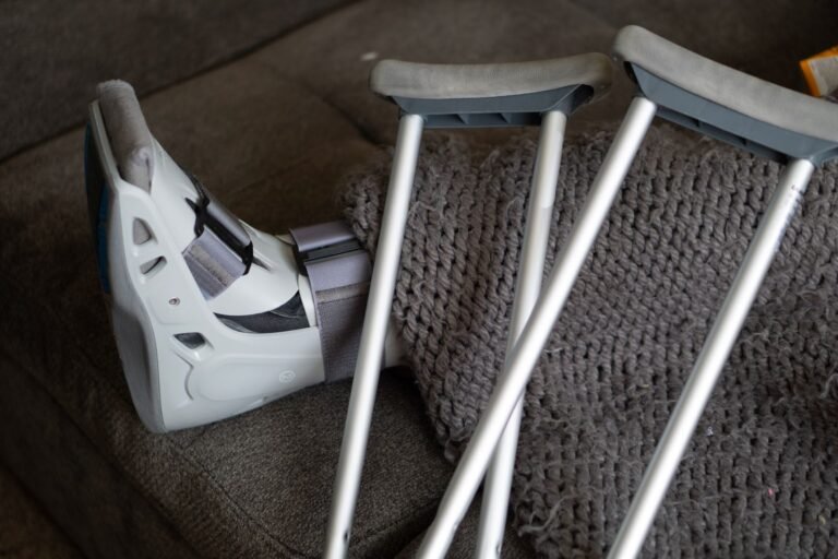 Cartiva implant failure: orthopedic walking boot and crutches resting on a couch at home