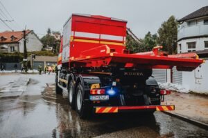 Week after a car accident: red tow truck parked on a wet city street on a rainy day