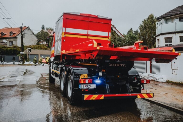 Week after a car accident: red tow truck parked on a wet city street on a rainy day