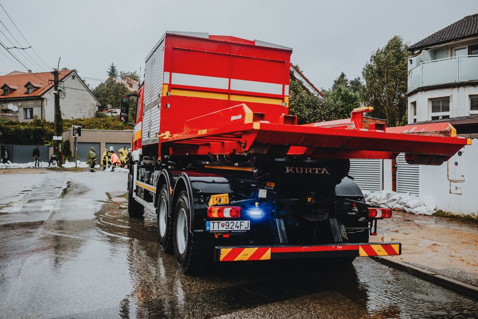 Week after a car accident: red tow truck parked on a wet city street on a rainy day
