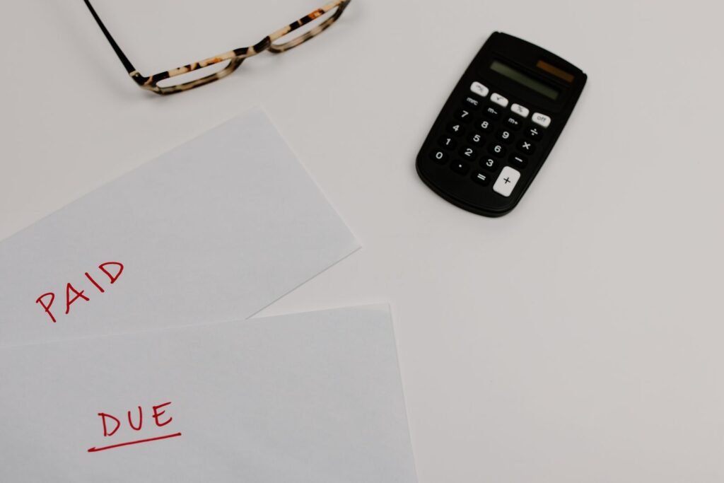 Week after a car accident: calculator beside bills marked paid and due on a desk