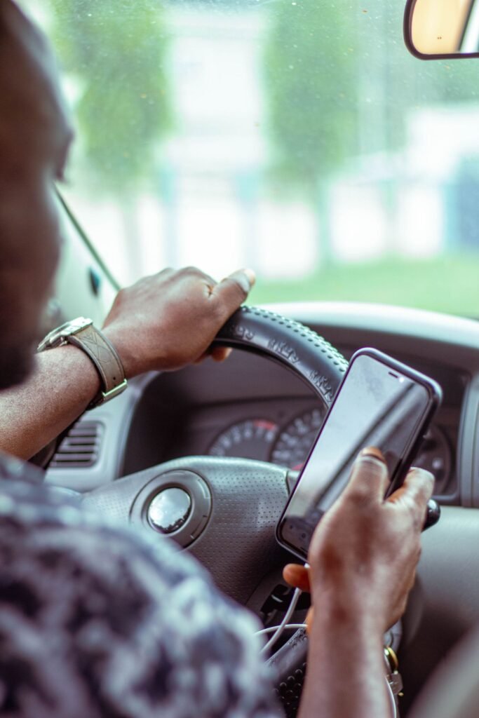 Distracted driving deaths: close-up of hands on a steering wheel with a smartphone in view