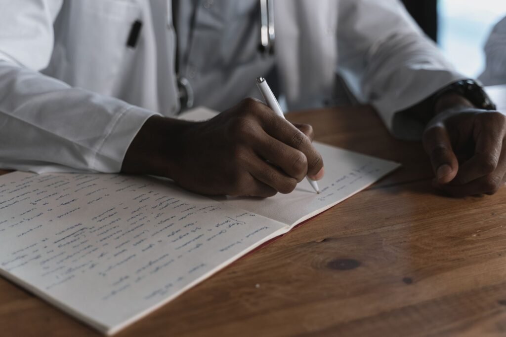 Dupixent claim evidence: close-up of a clinician's hand writing notes in a medical notebook on a desk