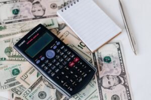 Depo-Provera settlement: calculator, notepad and pen on top of U.S. dollar bills, representing settlement value questions