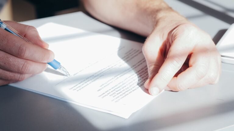 Zantac settlement: close-up of a hand signing a document with a blue pen, representing a settlement agreement