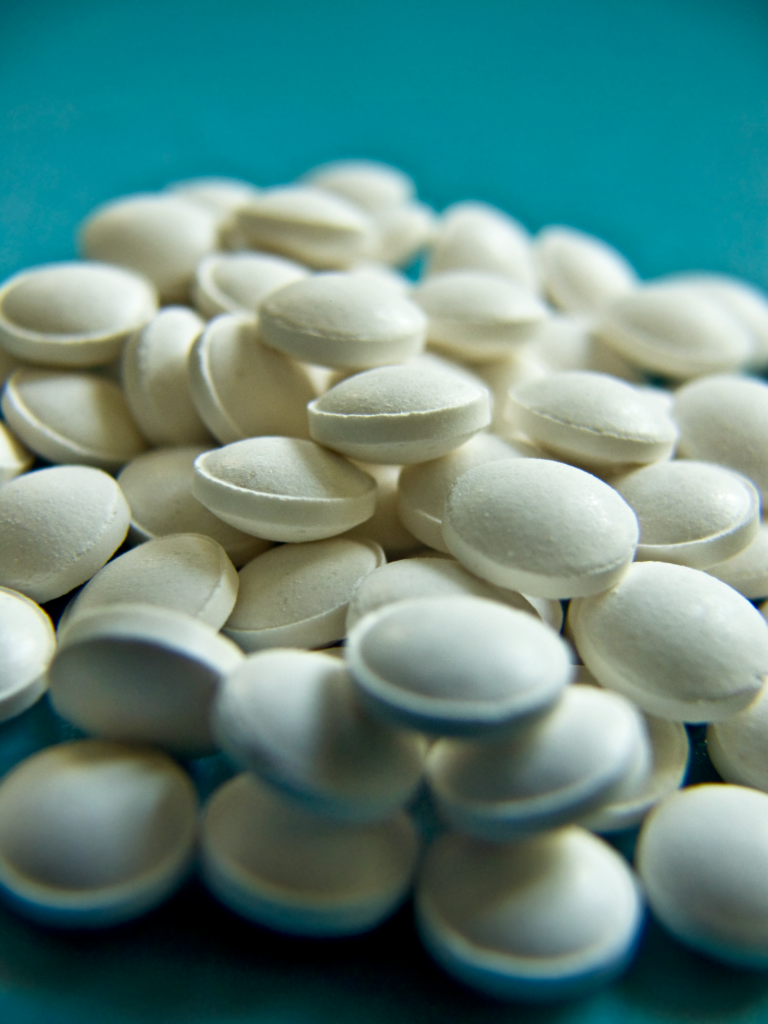 Zantac settlement: plain white round tablets scattered on a blue surface, with no brand markings
