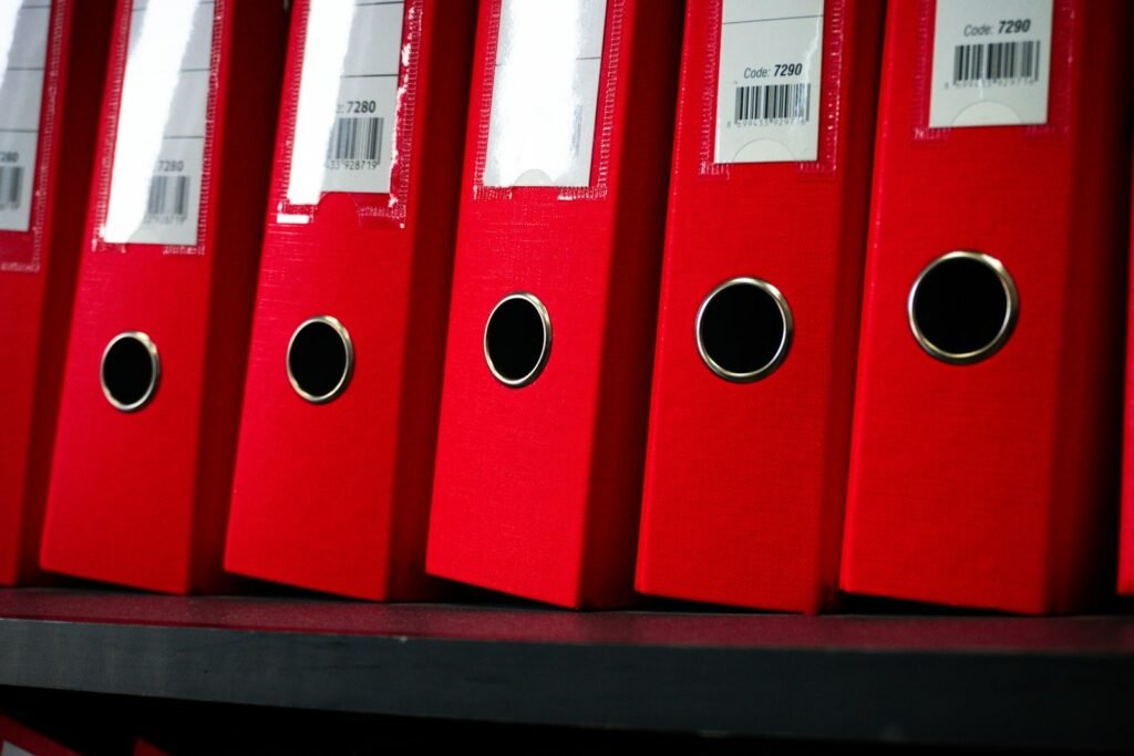 Red file folders neatly arranged on a shelf for organizing medical records