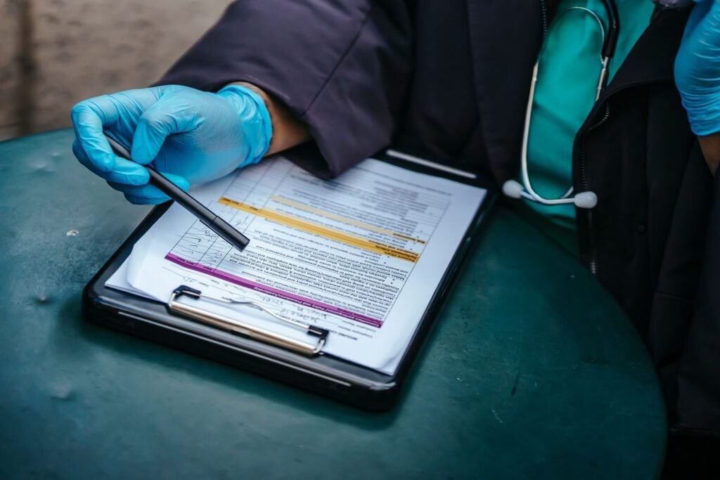 Gloved healthcare worker reviewing medical documents on a clipboard during a follow-up visit