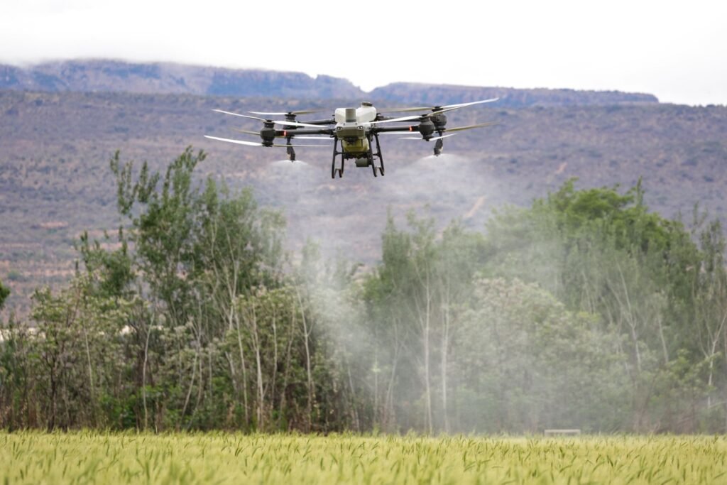 Drone spraying crops in a field with mountains behind, the kind of exposure behind chlorpyrifos claims