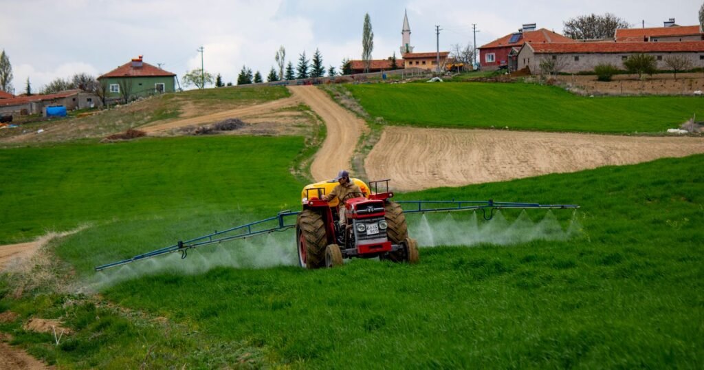 Tractor spraying pesticide across farm fields, the kind of exposure behind chlorpyrifos claims
