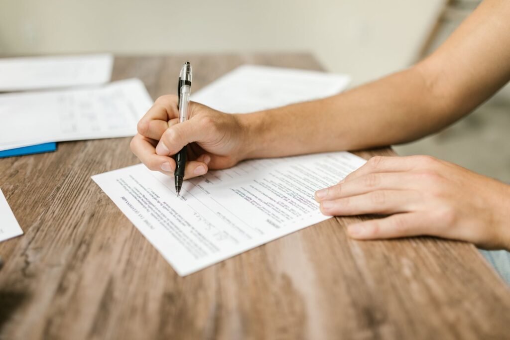 CIW abuse claims: hand filling out a claim form with a pen at a table