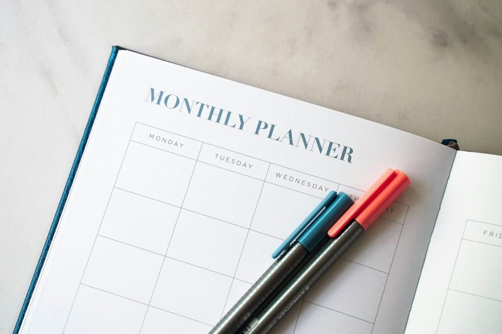 Open planner with two pens on a desk for tracking dates
