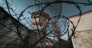 Prison watchtower behind barbed wire, illustrating the Dr. Scott Lee lawsuit FAQ for CIW survivors