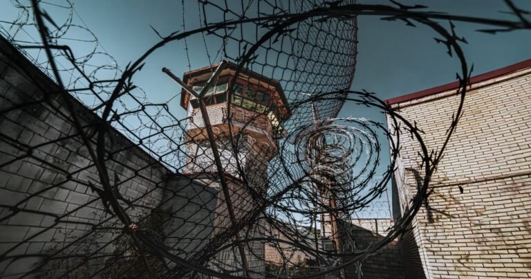 Prison watchtower behind barbed wire, illustrating the Dr. Scott Lee lawsuit FAQ for CIW survivors