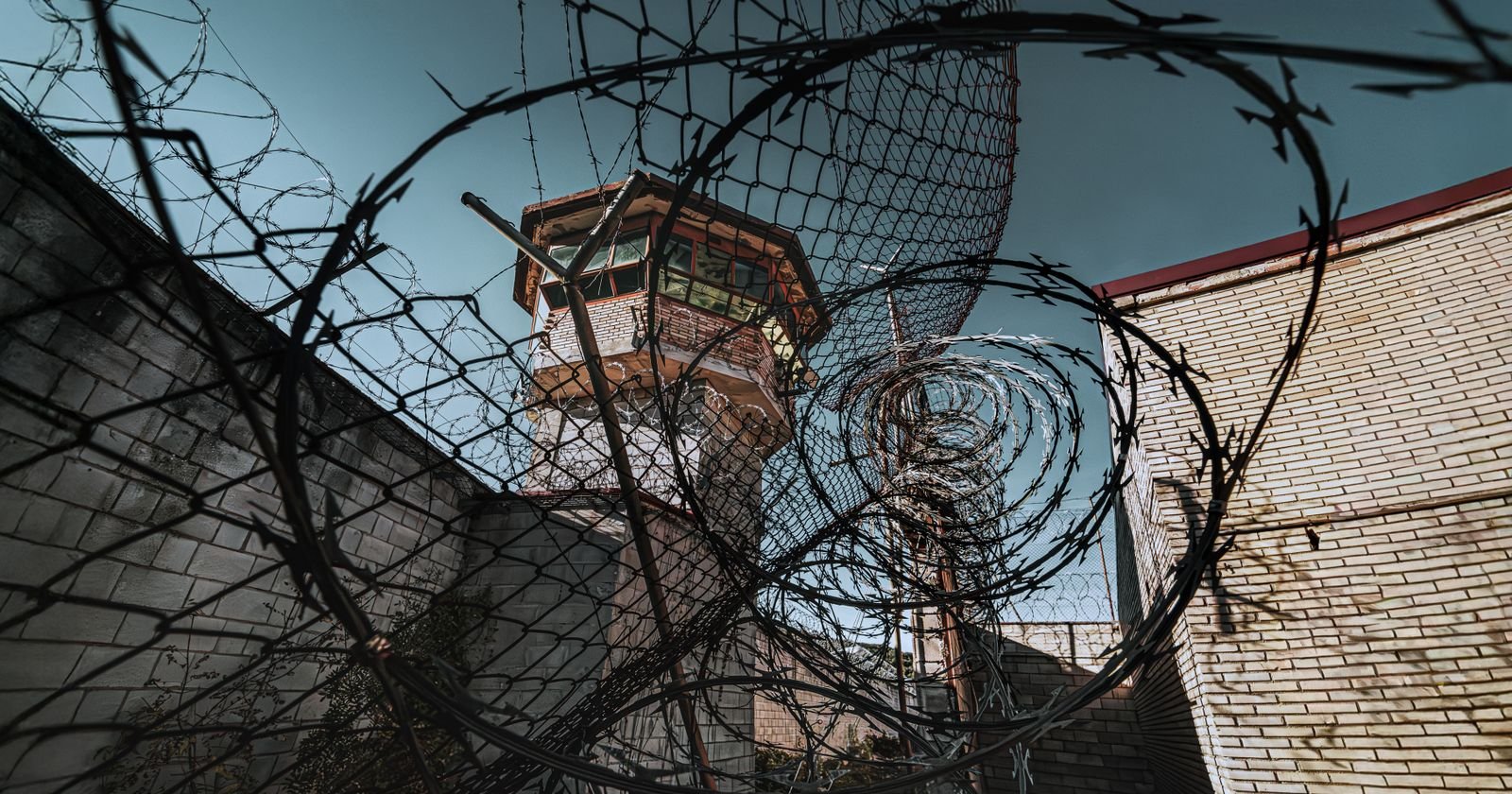 Prison watchtower behind barbed wire, illustrating the Dr. Scott Lee lawsuit FAQ for CIW survivors