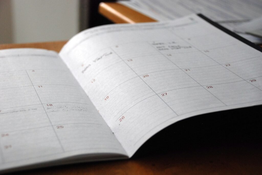 Open monthly planner on a wooden desk, used to prepare dates before a Dupixent lymphoma case review