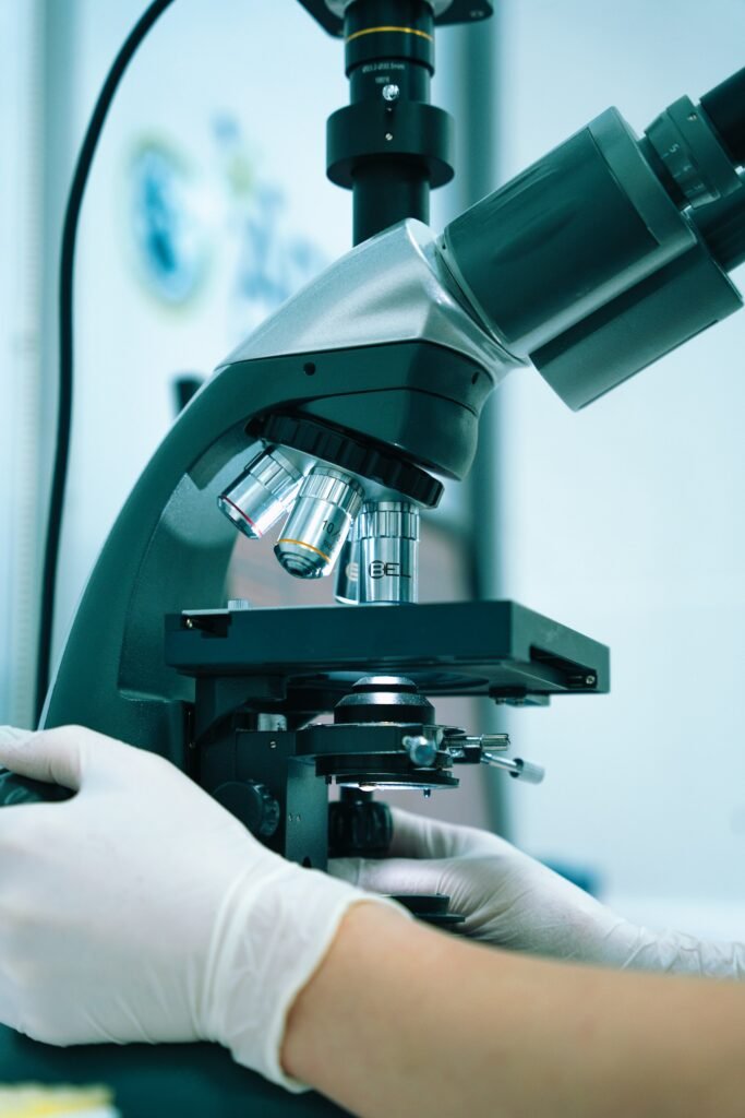 Gloved hand operating a laboratory microscope, where biopsy samples help sort out CTCL vs eczema