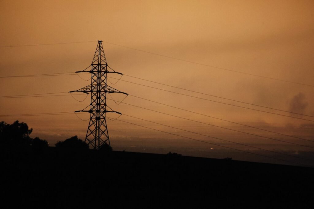Power transmission tower silhouetted at sunset, a reminder of the equipment behind utility wildfire settlements